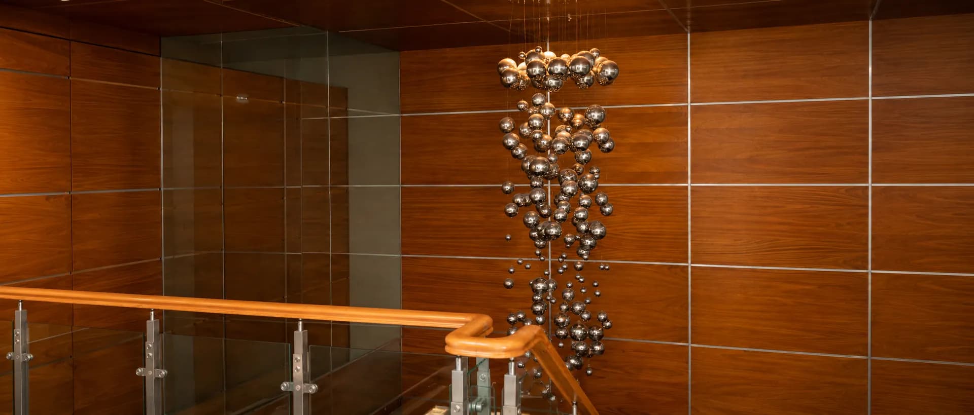 Lobby del estudio con lámpara de esferas cromadas y paneles de madera